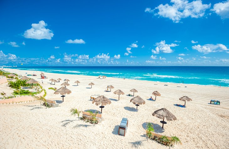 Palapas dotting a white-sand beach in Cancun