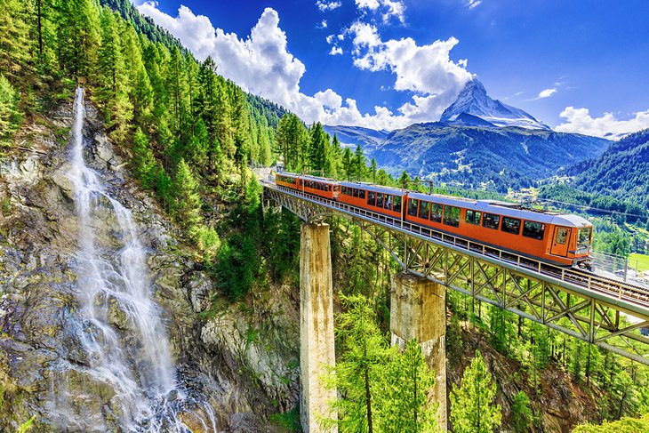 Train crossing a bridge in Switzerland with the Matterhorn in the distance