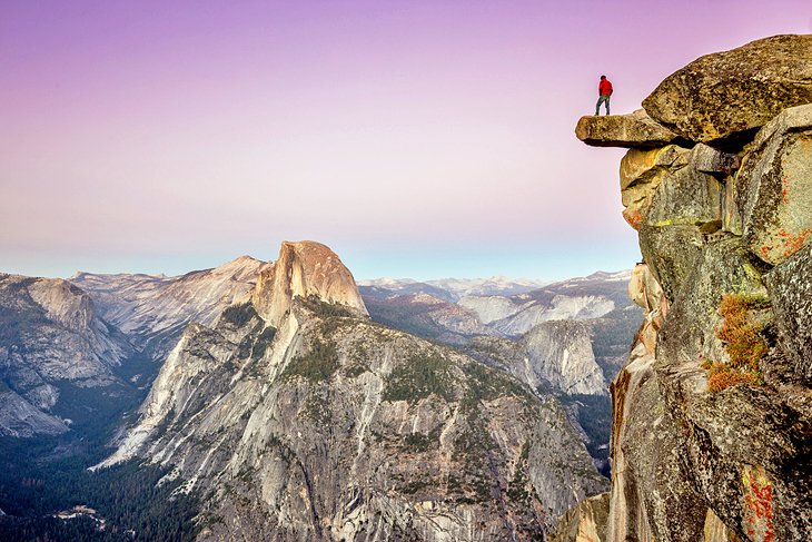 Hiker standing on Glacier Point overlooking Half Dome in Yosemite National Park