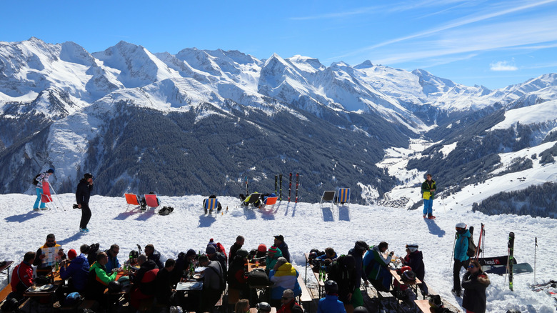 People relaxing in lounge chairs in the snow at Mayrhofen ski resort in Austria on a sunny day