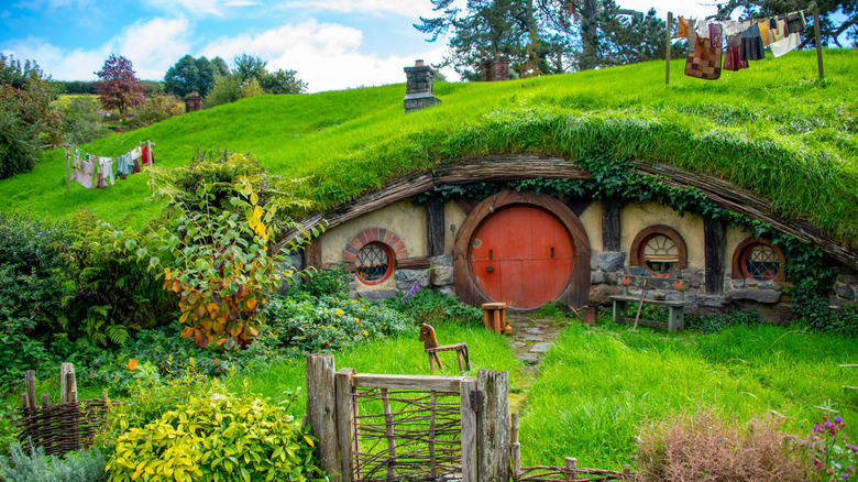 Hobbit Hole with red door and laundry hanging nearby in Hobbiton, New Zealand