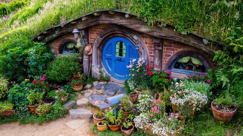 Hobbit Hole with blue door surrounded by flowers in Hobbiton, Matamata, New Zealand