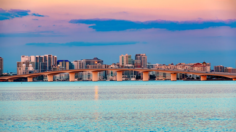 Twilight view of Sarasota, Florida skyline with blue water in the foreground and a beautiful pink and purple sunset