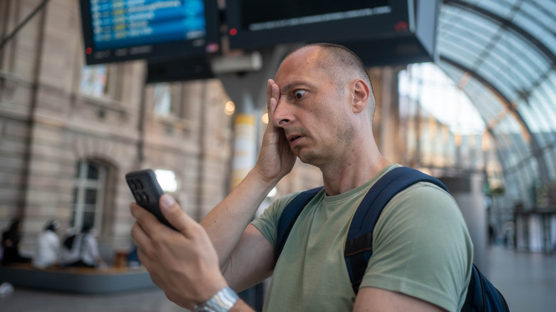 Agitated traveler checking their phone while standing in an airport terminal
