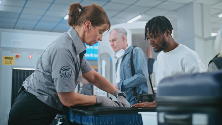 TSA agent inspects a passenger's bag in the bin at an airport security checkpoint