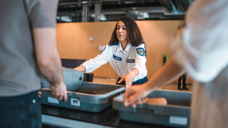 Close-up portrait of an officer conducting luggage inspection at an airport security checkpoint