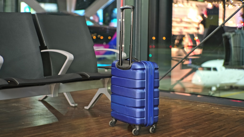 View of a blue suitcase left unattended in an airport departures area