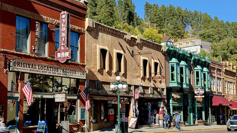 View of the original Saloon No. 10 building on Main Street in Deadwood, South Dakota, with Wild Bill Bar signage and American flags.