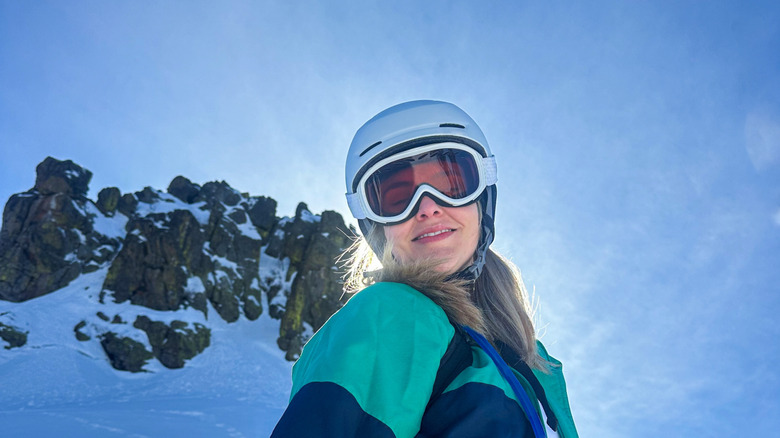 A happy blonde woman takes a break from skiing and smiles at the top of a snowy mountain top at China Peak, California, USA