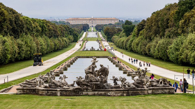 Panoramic view of the Royal Palace of Caserta with statues in the foreground