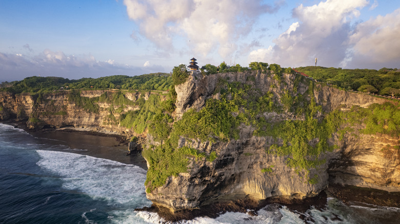 View of Uluwatu Temple, Bali, on its rocky cliff on a sunny day approaching dusk
