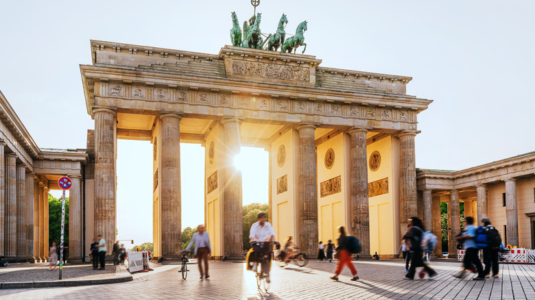 Tourists walk around the Brandenburg Gate in Berlin