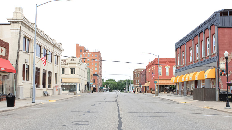 View of vintage storefronts, some with colorful awnings and American flags, in downtown Abilene, Kansas on a cloudy day