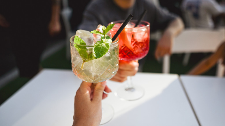 Two travelers toasting with an Aperol Spritz and Hugo Spritz,