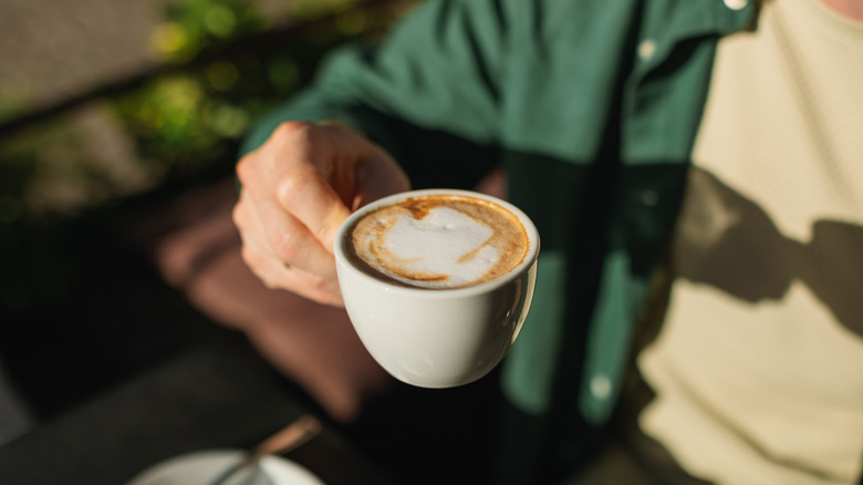 Man sitting at an outdoor cafe drinking a cappuccino