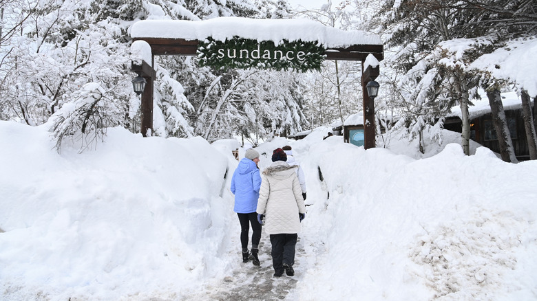 Two people walk in the snow under a gateway reading "Sundance" in Utah