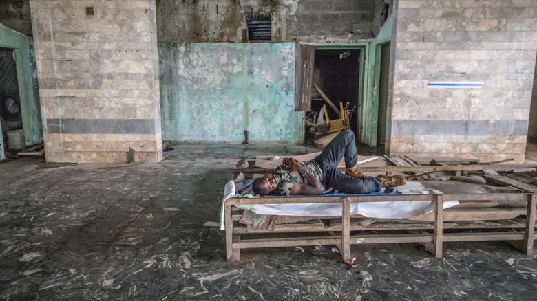Man sleeping on a bed inside the abandoned Ducor Palace Hotel