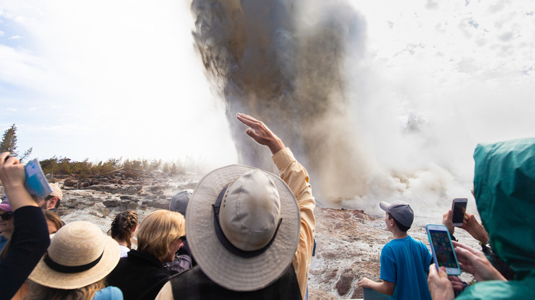 Tourists take in an eruption of Steamboat Geyser at Yellowstone National Park