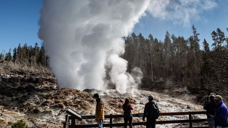 Steamboat Geyser erupts with tourists in the foreground at Yellowstone National Park