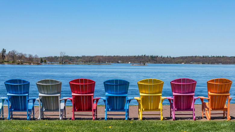 Row of colorful Adirondack chairs next to lake in Clayton