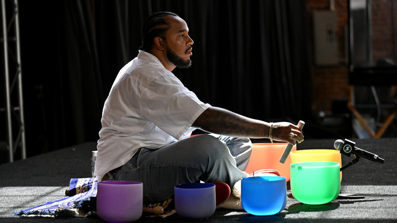 a musician plays different sized and colored singing bowls on a stage