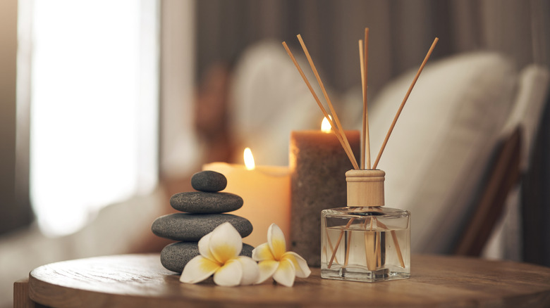 illuminated candles, incense, rocks, and flowers on a table