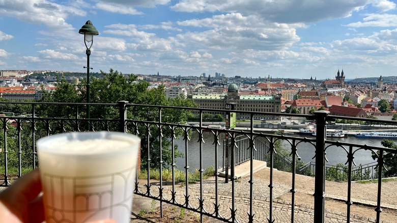 Person holding a full cup of beer overlooking Prague from Letna Beer Garden