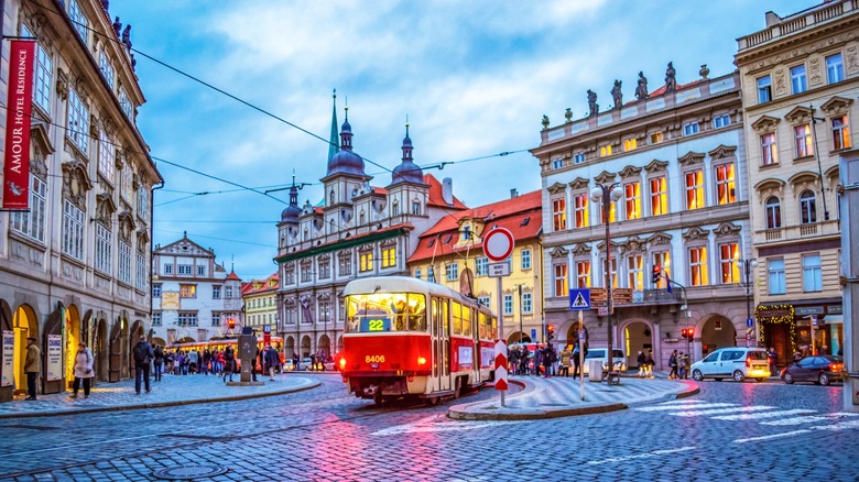 Red tram traveling through Malostranske Namesti at dusk