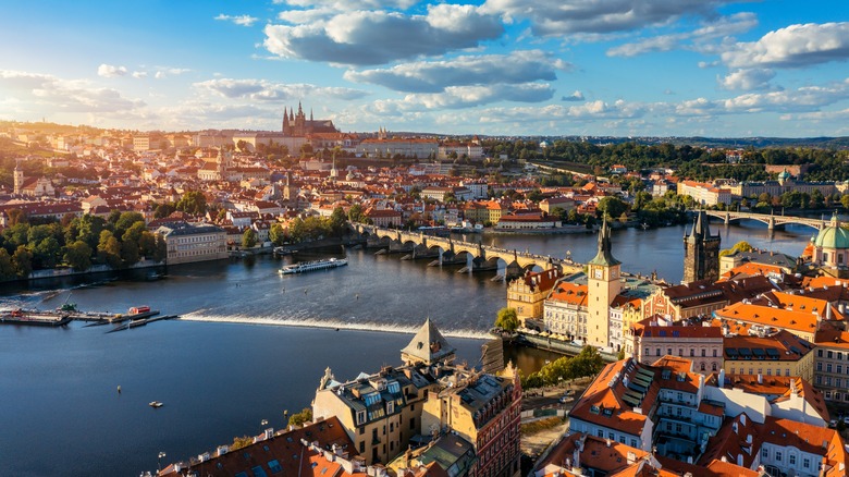 Expansive Prague cityscape with Prague Castle, Charles Bridge, and Old Town, on a sunny summer evening