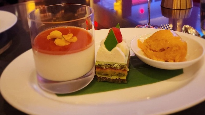 three dishes on a single platter with neon lights and bar in background