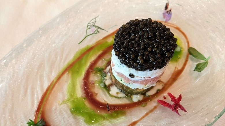 cup filled with caviar parfait with colorful sauces on the plate