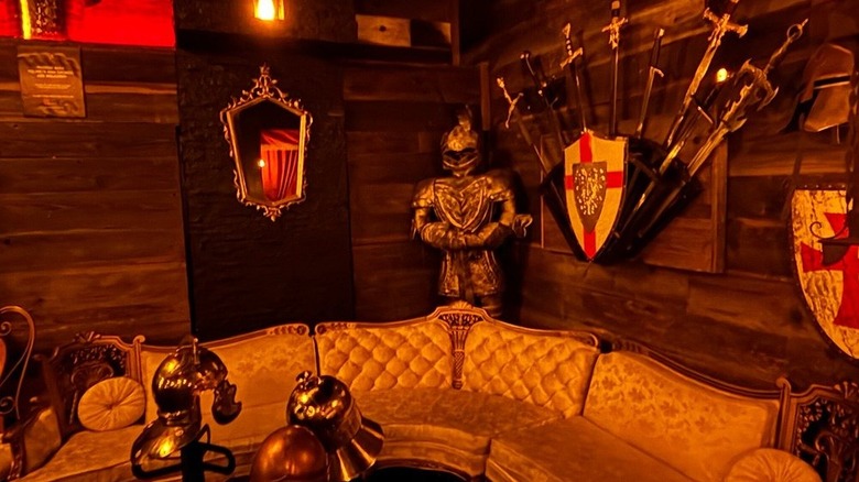 sofa with medieval decor in background, swords and suit of armor