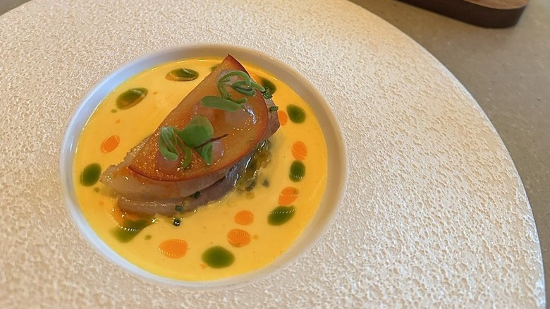 plate of food in a yellow sauce with fine herbs on top