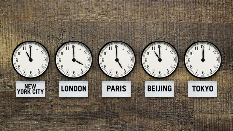 five clocks side by side showing the time in different cities