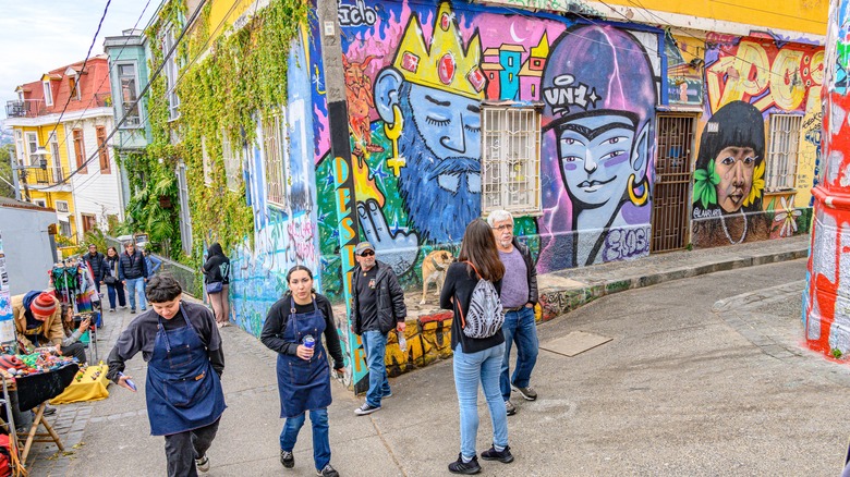 people standing in a street covered in colorful murals