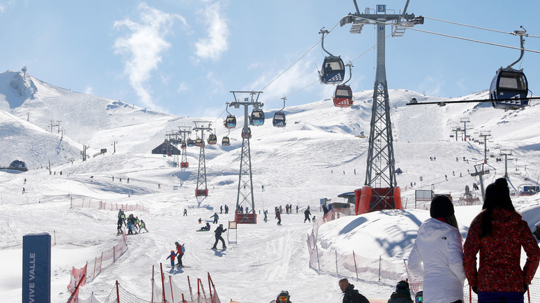 ski lifts and skiiers going down a large mountain slope
