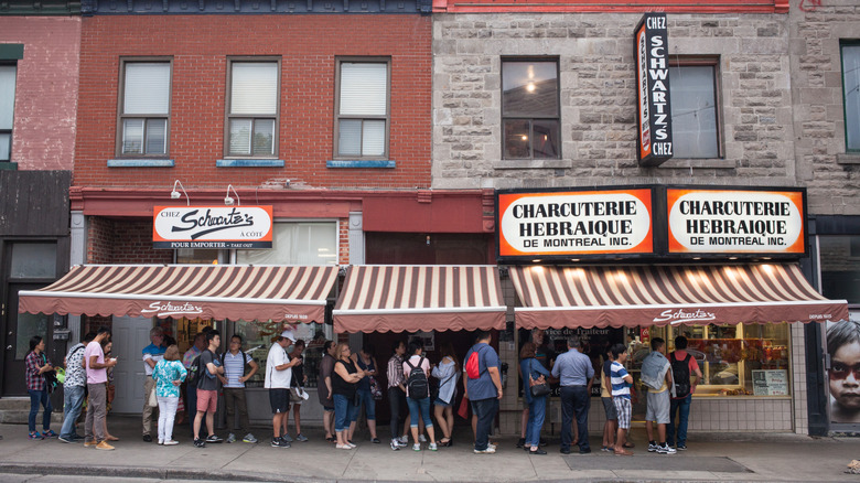 a line of people waiting outside a building with signs that say "schwarts"