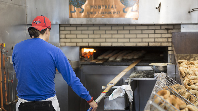 worker placing bagels in a brick oven