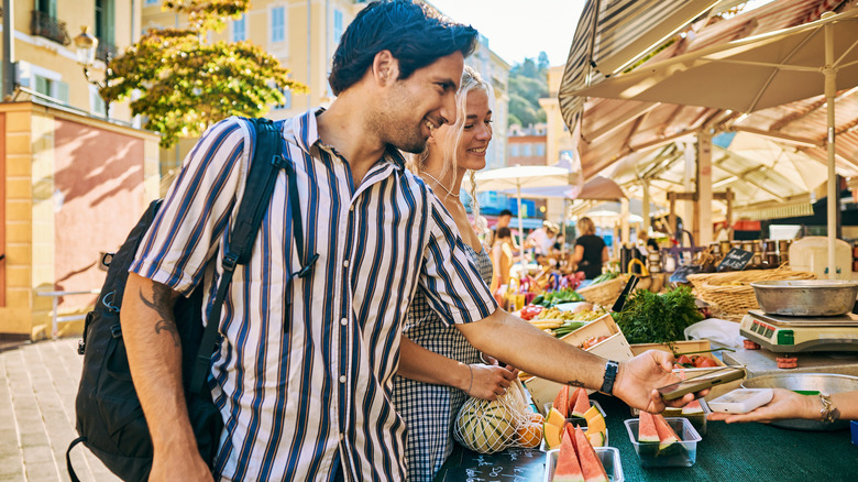 a couple making a purchase at an outdoor food market