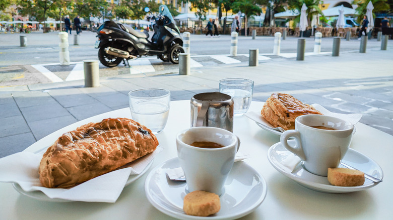 coffees and pastries on a table outside looking over a street