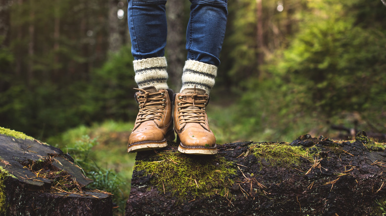 Person in hiking boots with thick socks standing in a mossy forest