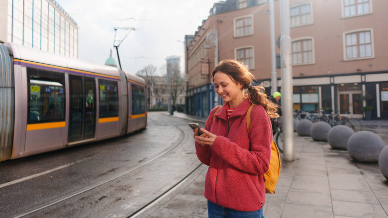 Smiling traveler checking their phone standing near a city street