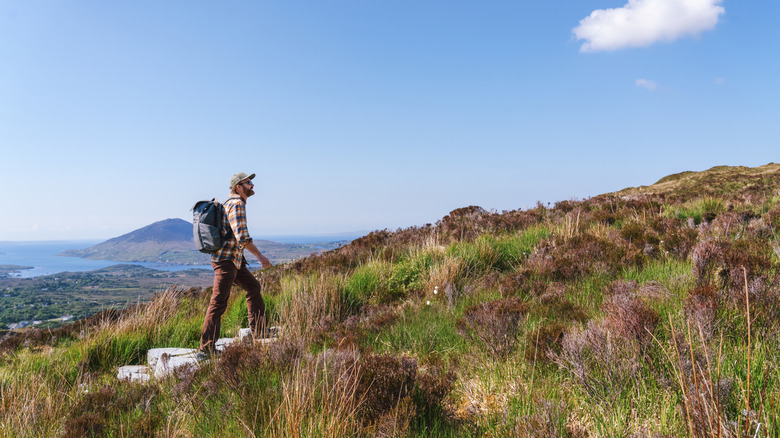 Hiker walking up stone steps wearing a backpack, cap, and sunglasses