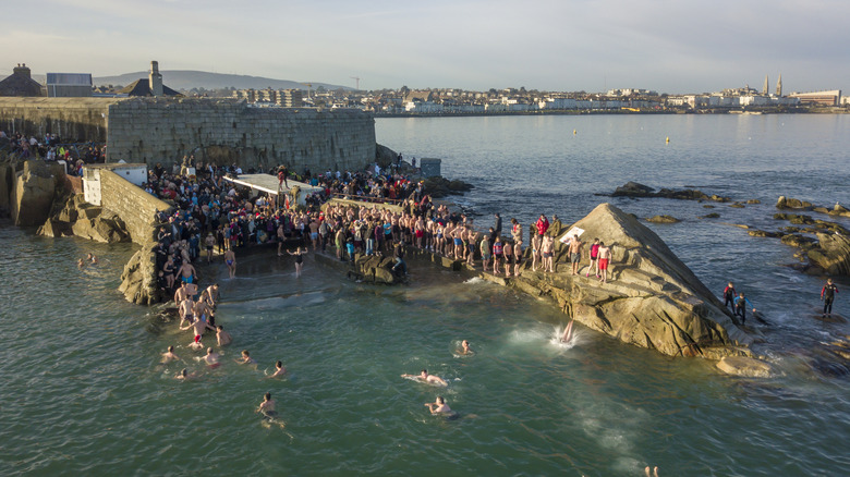 People in swimsuits jumping into the sea off a natural pier in Dublin, Ireland