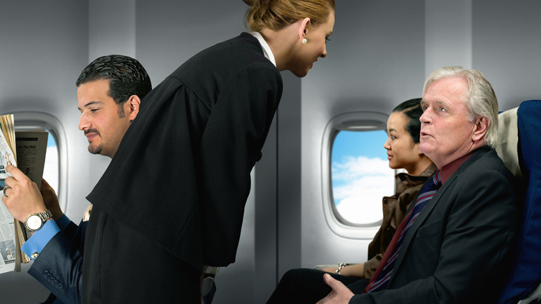 A passenger speaking with a flight attendant