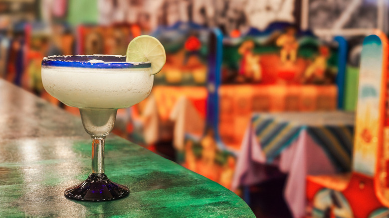 A frozen margarita sits on a bar at a Mexican restaurant.
