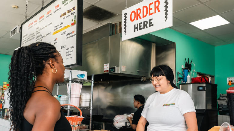 A customer speaks to a food service worker in a Mexican-style restaurant.