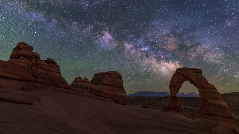 A brilliant, colorful Milky Way rises behind Delicate Arch over the La Sal Mountains in Arches National Park, Utah.