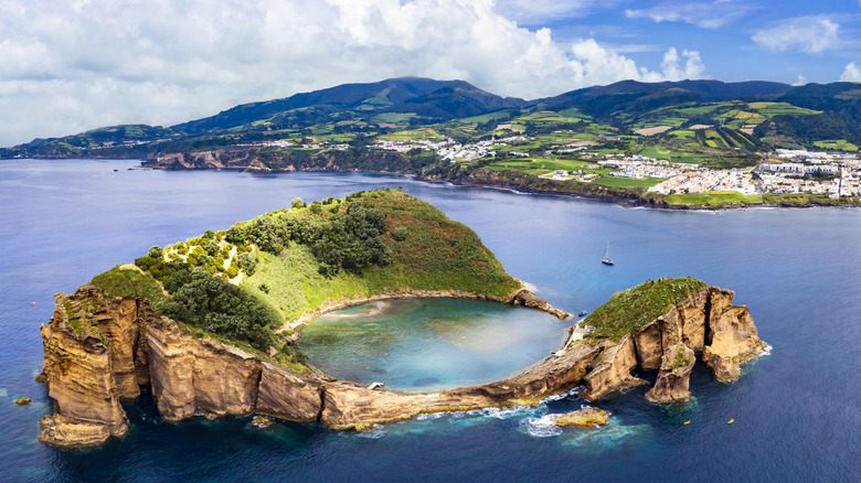 Small volcanic island with round beach across the water from the Azores Island of São Miguel, Portugal