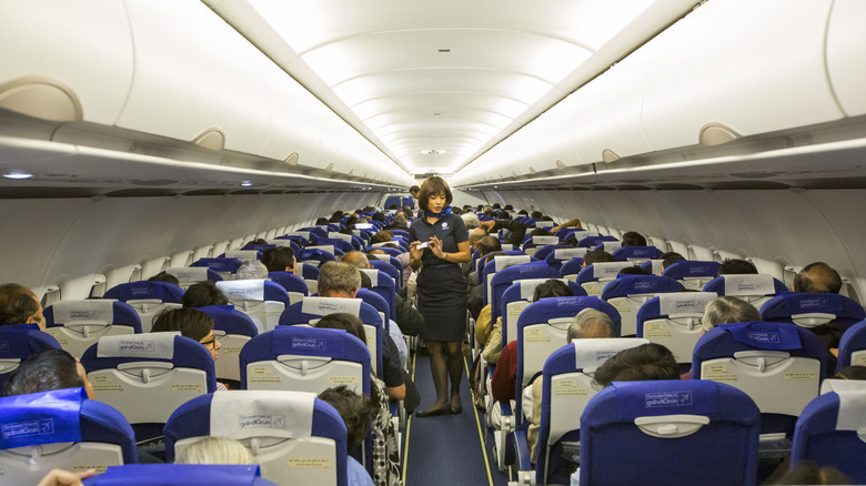 A flight attendant addresses passengers during a flight